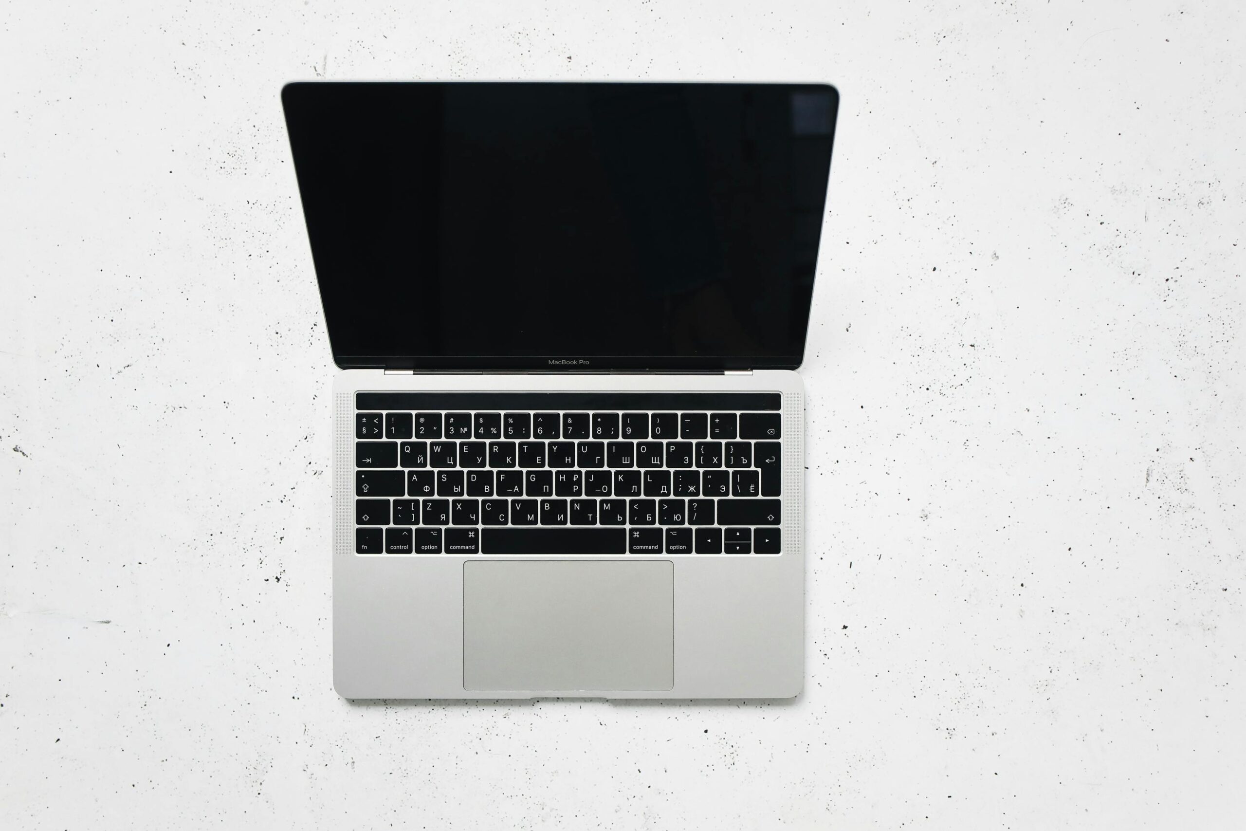 A sleek open laptop placed on a white marble surface, captured from above.